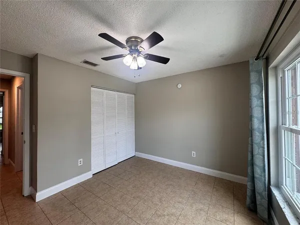 an empty room with windows and fan