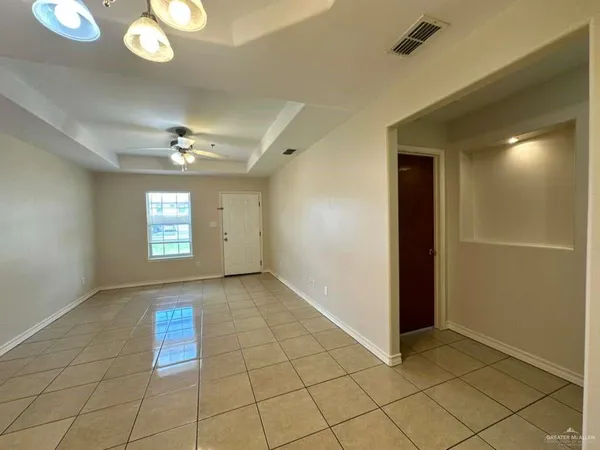 an empty room with chandelier fan and windows