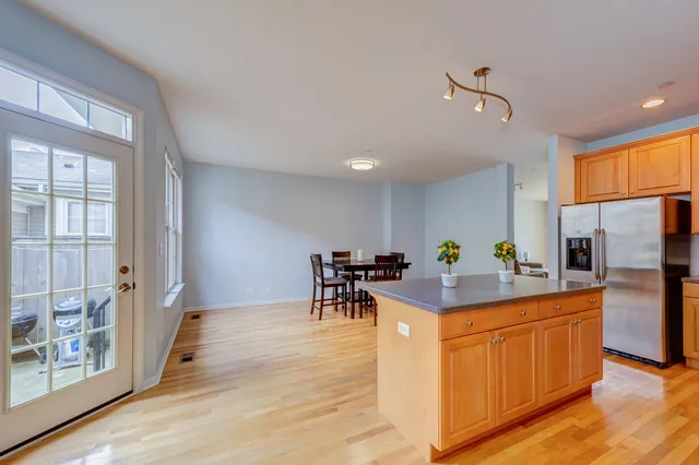 a kitchen with stainless steel appliances kitchen island granite countertop a table chairs and a refrigerator