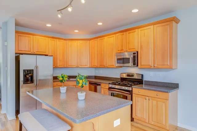 a kitchen with stainless steel appliances a stove a sink a microwave a refrigerator and cabinets