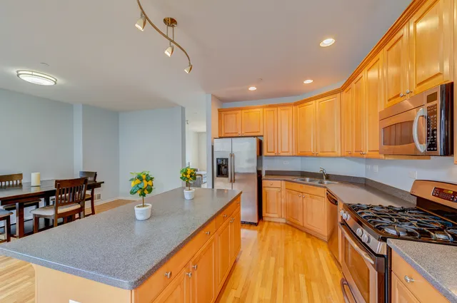 a kitchen with stainless steel appliances granite countertop a stove top oven a dining table and chairs with wooden floor