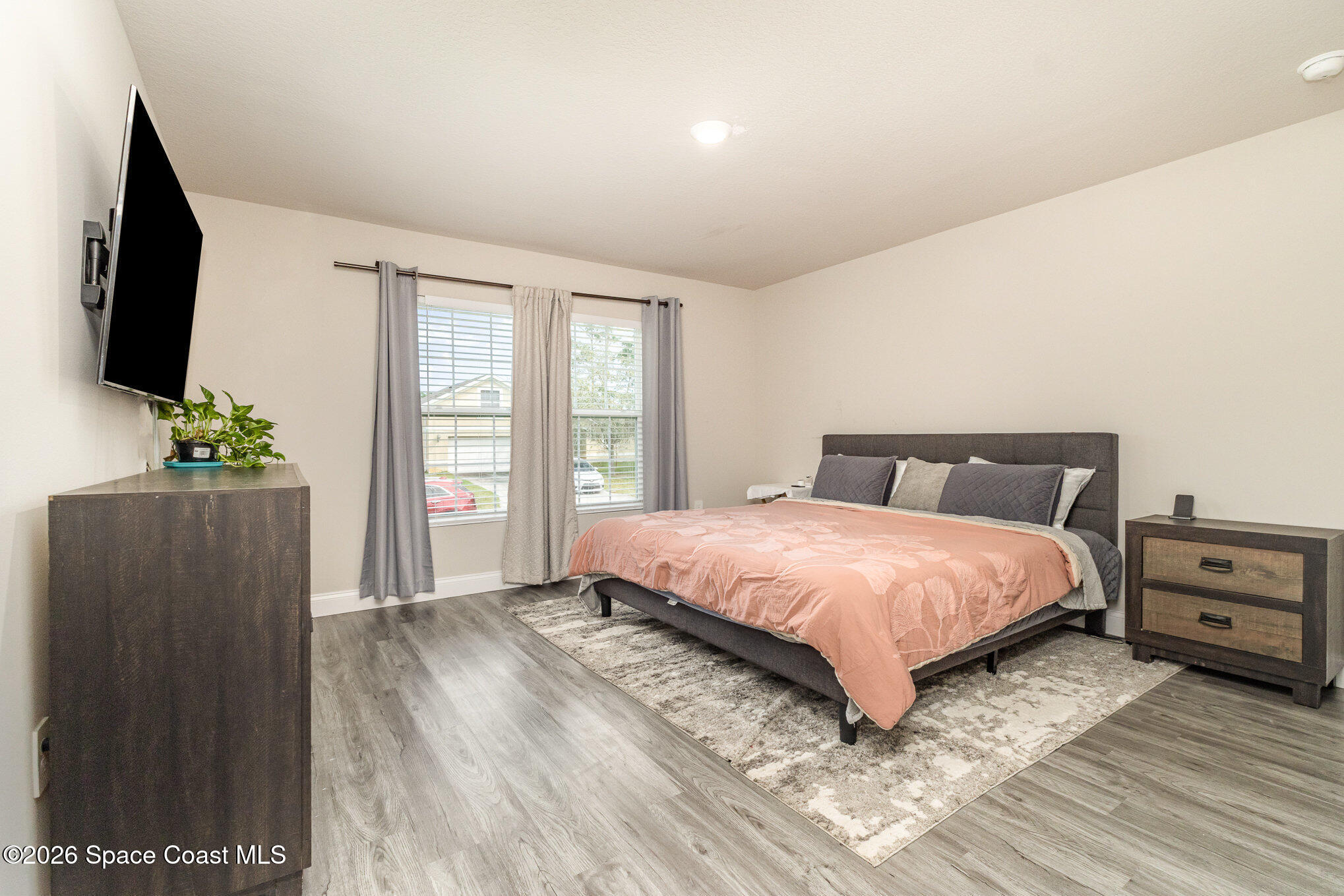 866 Carnival Road Southeast Palm Bay, FL 32909 - Photo 18 of 28 a bedroom with a bed and a flat tv screen on a dresser