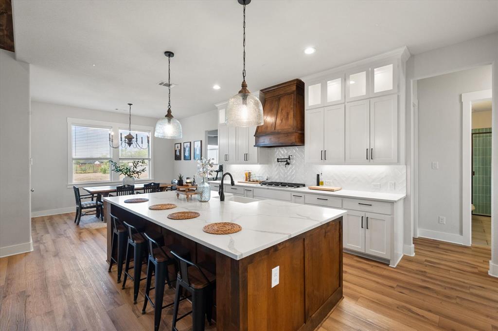 8221 David Lane Midlothian, TX 76065 - Photo 12 of 34 Kitchen featuring white cabinetry, decorative backsplash, a kitchen breakfast bar, light stone counters, and recessed lighting Dining area in sight