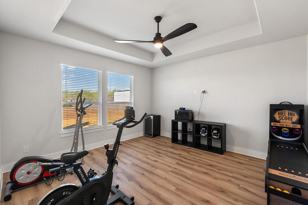 8221 David Lane Midlothian, TX 76065 - Photo 17 of 34 Exercise room with a tray ceiling, light wood-style flooring, and ceiling fan