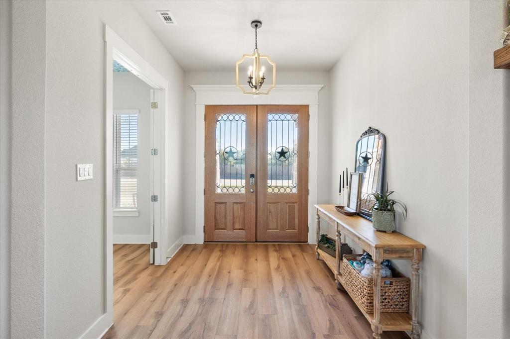8221 David Lane Midlothian, TX 76065 - Photo 5 of 34 Foyer entrance with light wood-style floors, a chandelier, and a textured wall