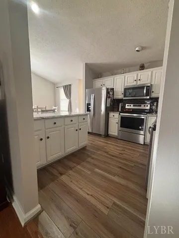 a kitchen with granite countertop a refrigerator and a stove top oven
