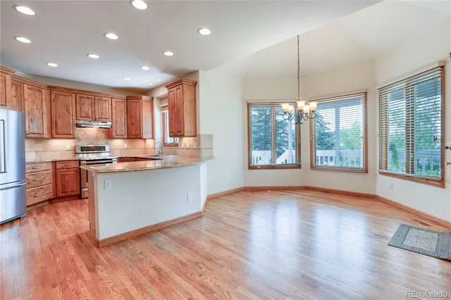 a kitchen with stainless steel appliances granite countertop wooden floors refrigerator and window
