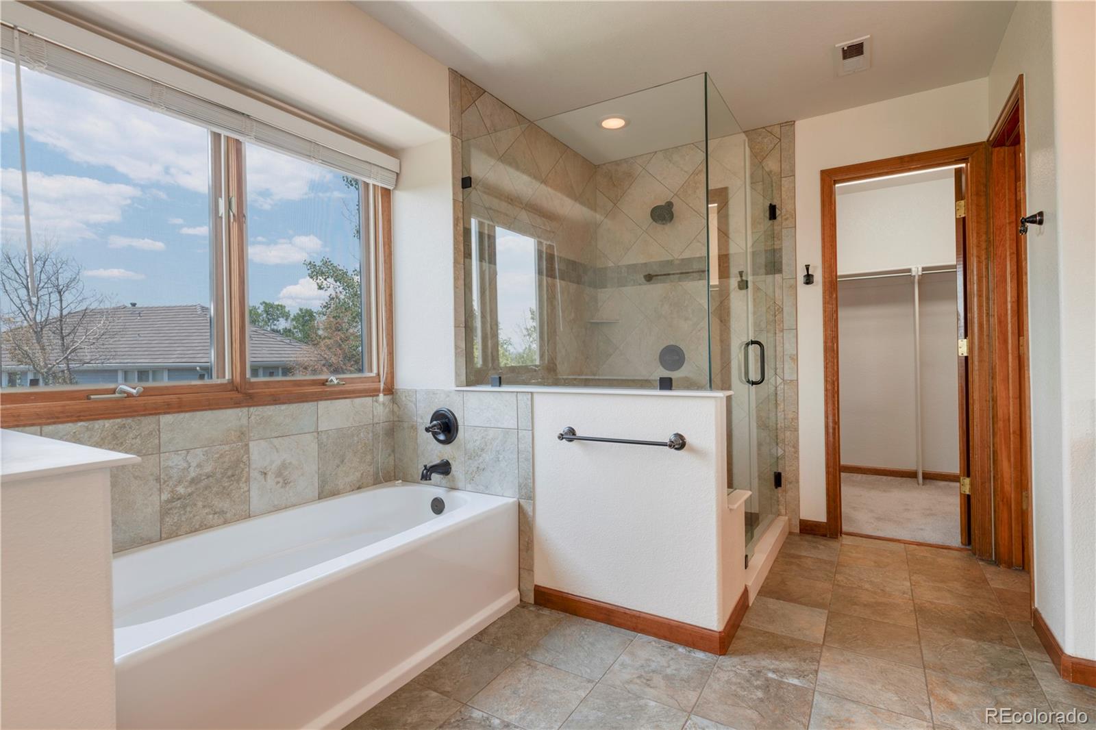 3756 West 100th Avenue Westminster, CO 80031 - Photo 25 of 45 a bathroom with a bathtub a shower a sink and a large window