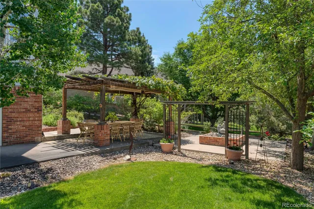 a view of backyard with table and chairs a fire pit and large trees