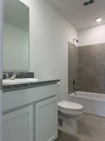 a bathroom with a granite countertop toilet a sink and a mirror