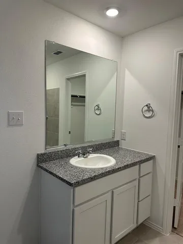 a bathroom with a granite countertop sink and a mirror