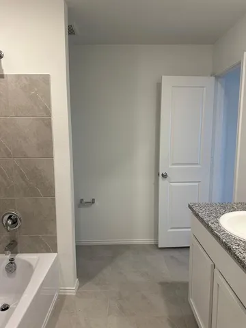 a bathroom with a granite countertop sink and a bathtub