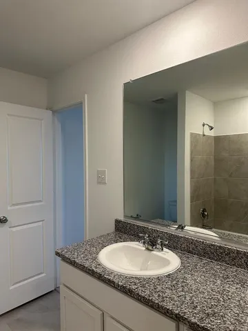 a bathroom with a granite countertop sink and a mirror
