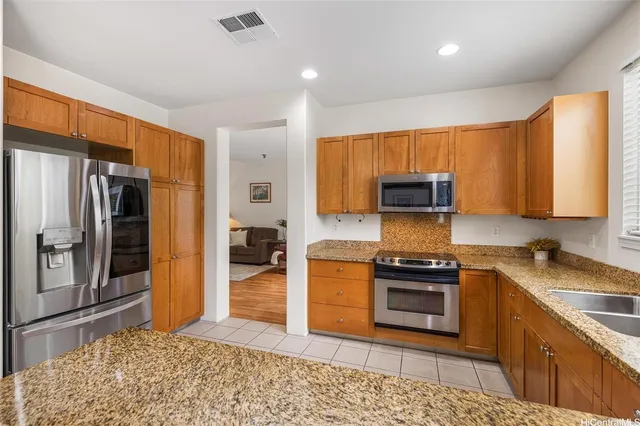 a kitchen with stainless steel appliances granite countertop a stove a sink and a refrigerator