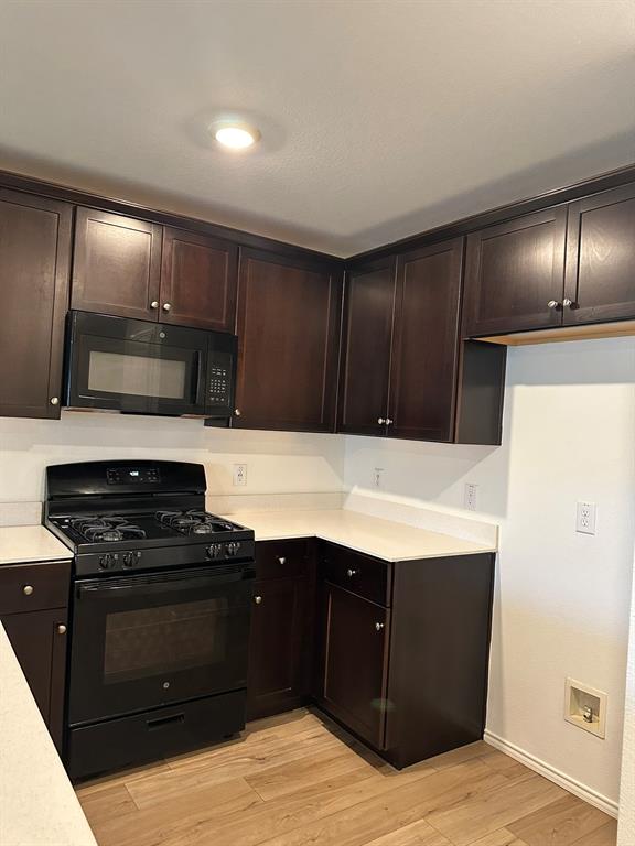 5906 Nyquist Way Forney, TX 75126 - Photo 2 of 27 Kitchen with black appliances, light countertops, dark brown cabinets, and light wood-style flooring