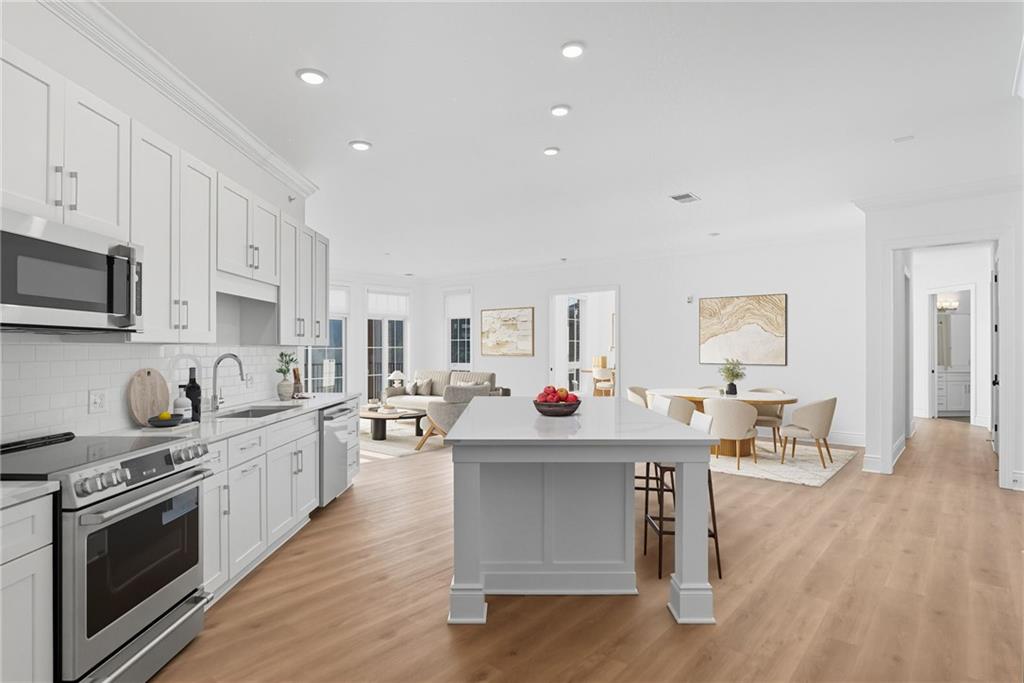 1 1st Street, Unit 407 Oakmont, PA 15139 - Photo 7 of 40 a kitchen with stainless steel appliances a white stove top oven cabinets a dining table and chairs with wooden floor