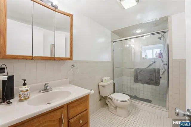 a bathroom with a toilet sink vanity granite and shower