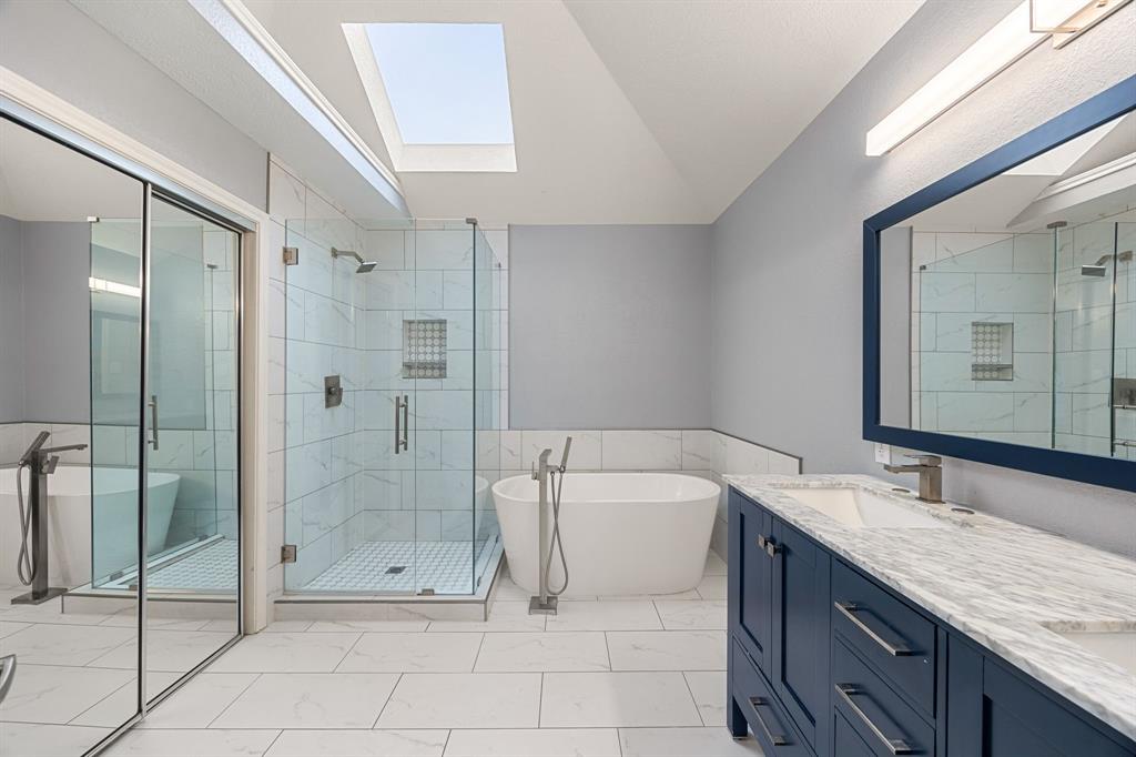 2016 Falcon Ridge Drive, Unit B Carrollton, TX 75010 - Photo 11 of 11 Full bathroom with a skylight, a freestanding bath, a stall shower, double vanity, and lofted ceiling