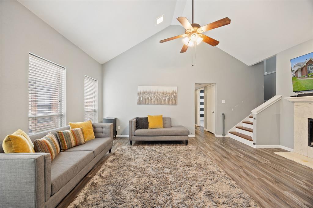 2016 Falcon Ridge Drive, Unit B Carrollton, TX 75010 - Photo 3 of 11 Living area featuring high vaulted ceiling, a fireplace, light wood-style floors, a ceiling fan, and stairway