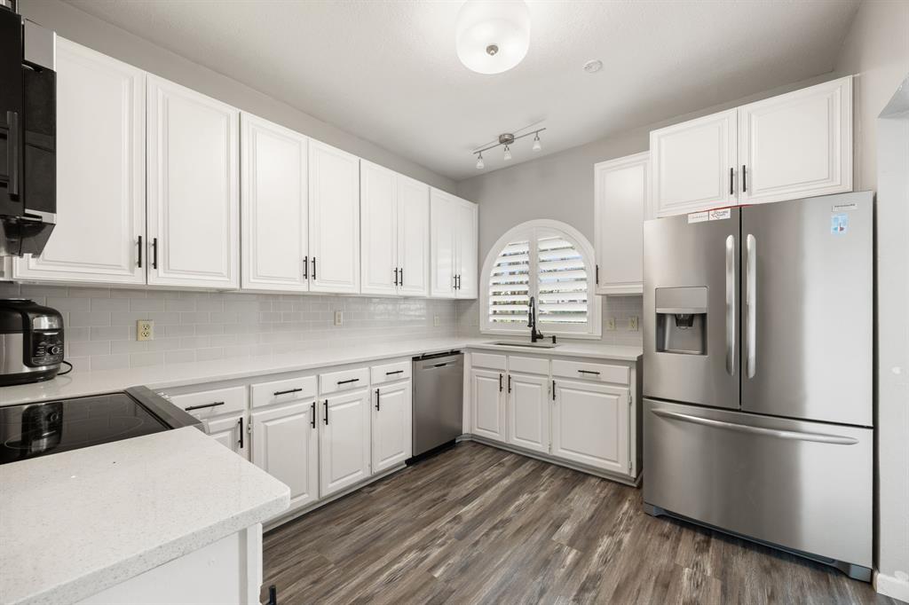 2016 Falcon Ridge Drive, Unit B Carrollton, TX 75010 - Photo 5 of 11 Kitchen with appliances with stainless steel finishes, white cabinets, decorative backsplash, dark wood finished floors, and light stone countertops