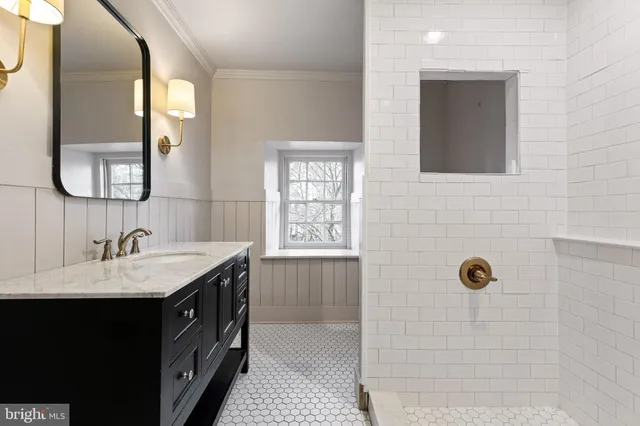 a bathroom with a granite countertop sink a mirror and shower