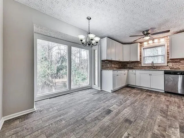 a kitchen with granite countertop a stove a sink and white cabinets with wooden floor