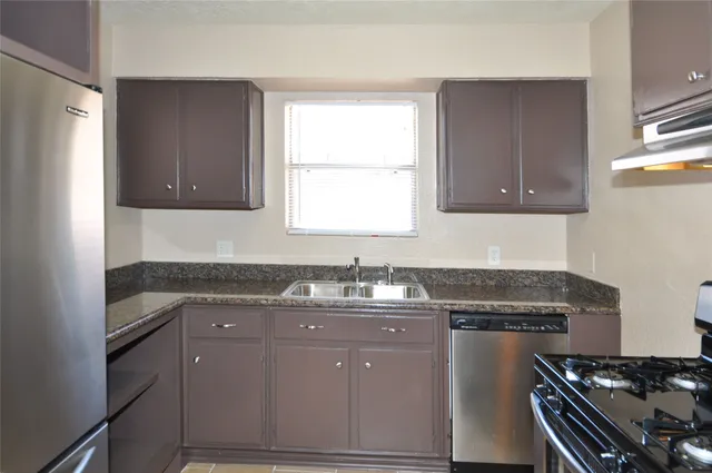 a kitchen with granite countertop a sink stove and cabinets