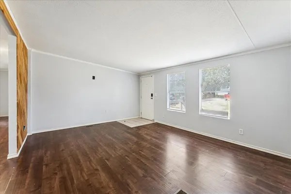 an empty room with wooden floor and windows