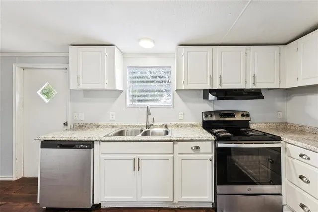 a kitchen with granite countertop a sink a stove and cabinets