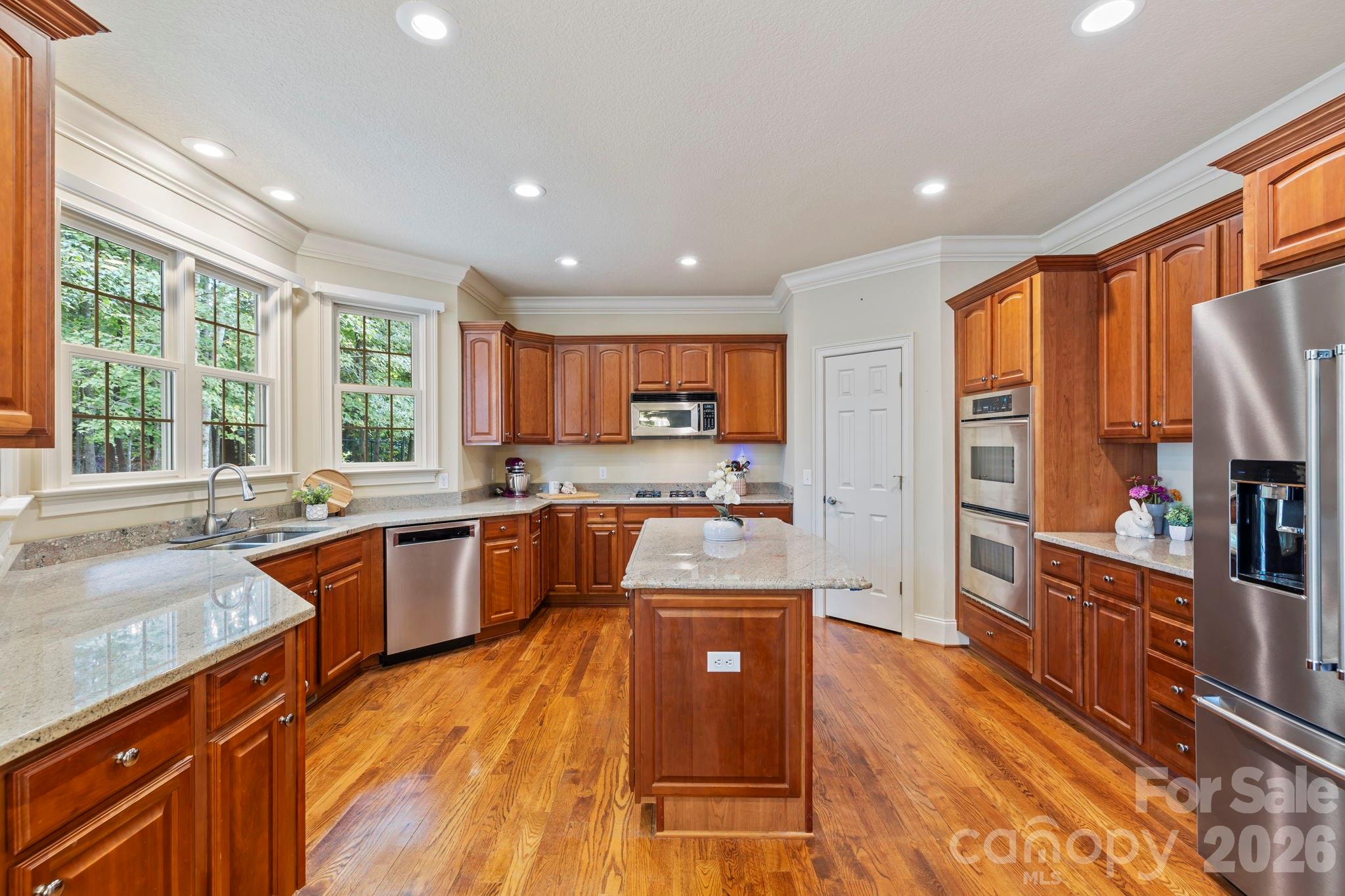 46 Beale Court Fletcher, NC 28732 - Photo 8 of 48 a large kitchen with stainless steel appliances granite countertop a refrigerator a sink dishwasher a stove and white countertops with wooden floor