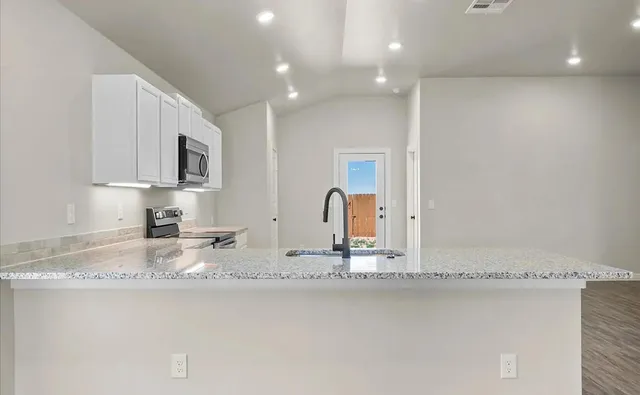 a kitchen with stainless steel appliances granite countertop a sink a stove and a microwave