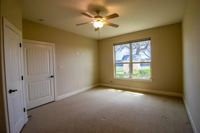 an empty room with windows and ceiling fan