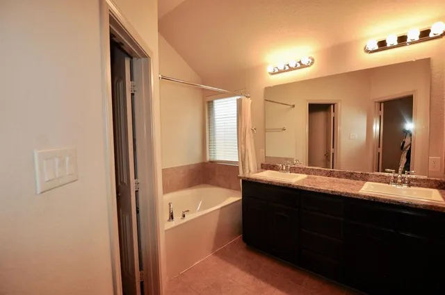 a bathroom with a double vanity sink and mirror with bathtub