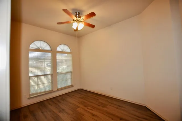 an empty room with wooden floor chandelier and fan