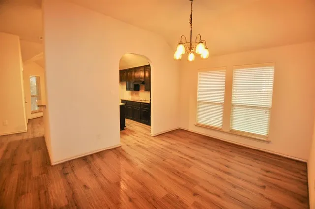a view of a room with wooden floor kitchen chandelier and a window