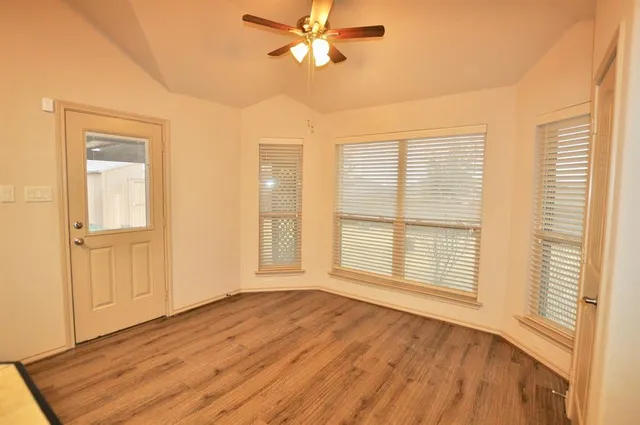 a view of an empty room with a window and wooden floor