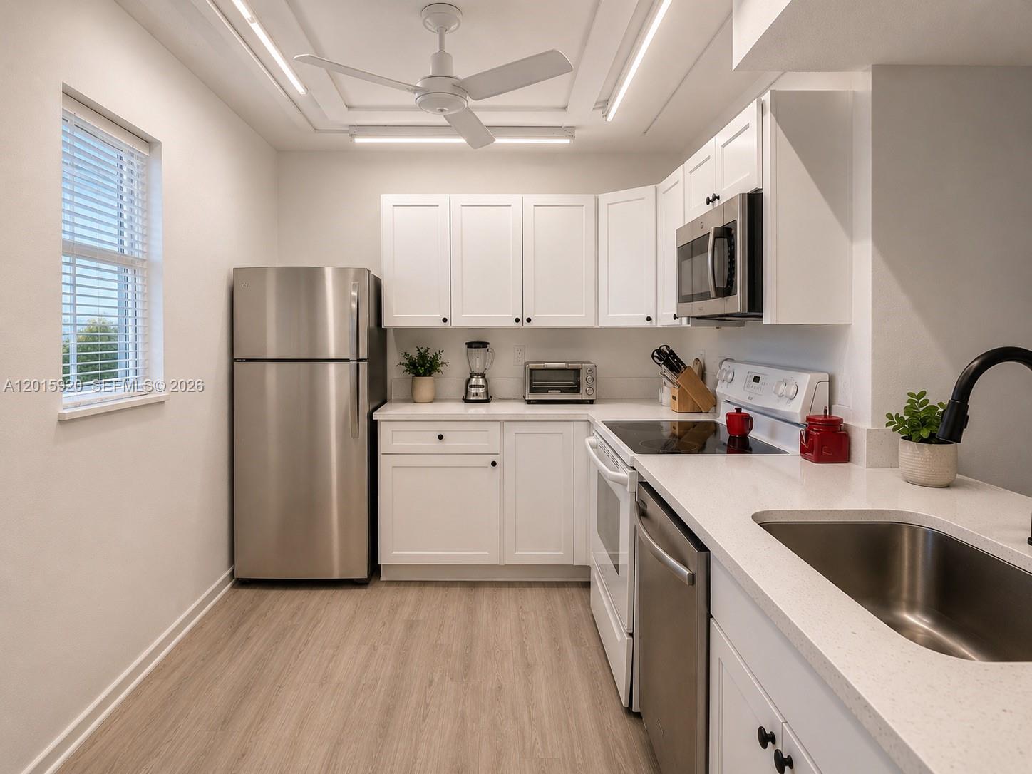 14170 Southwest 84th Street, Unit 404F Miami, FL 33183 - Photo 2 of 18 a kitchen with a sink a refrigerator a microwave and cabinets