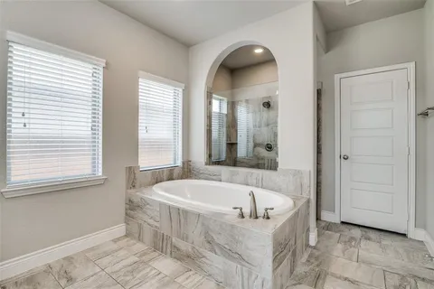 a white bath tub sitting in a bathroom next to a window