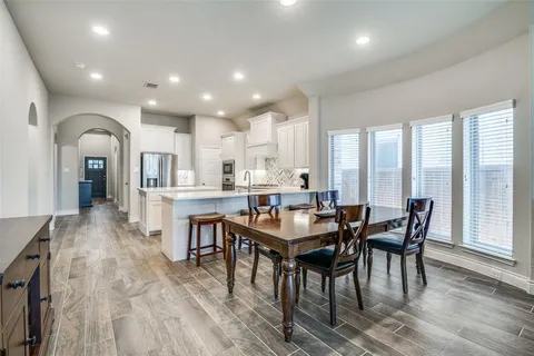 a dining hall with stainless steel appliances granite countertop a stove a sink a dining table and chairs