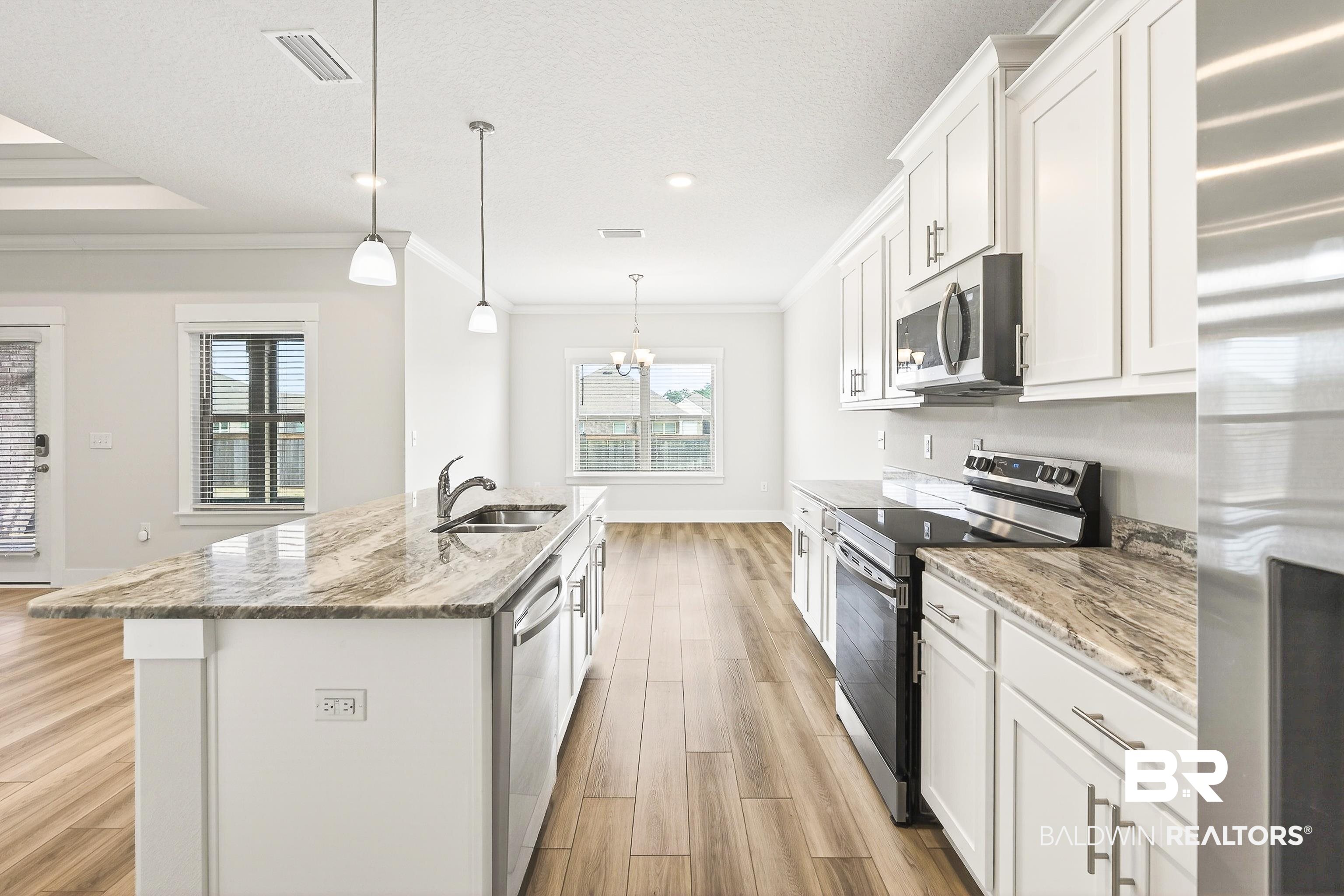 1728 Partridge Street Foley, AL 36535 - Photo 12 of 37 Kitchen featuring stainless steel appliances, white cabinets, a center island with sink, light wood-type flooring, and light stone countertops
