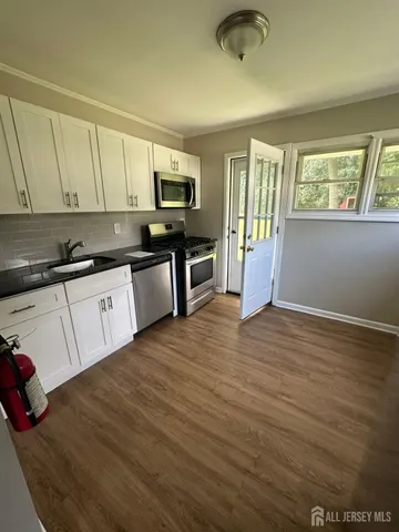 a kitchen with granite countertop a stove top oven a sink a counter space and cabinets