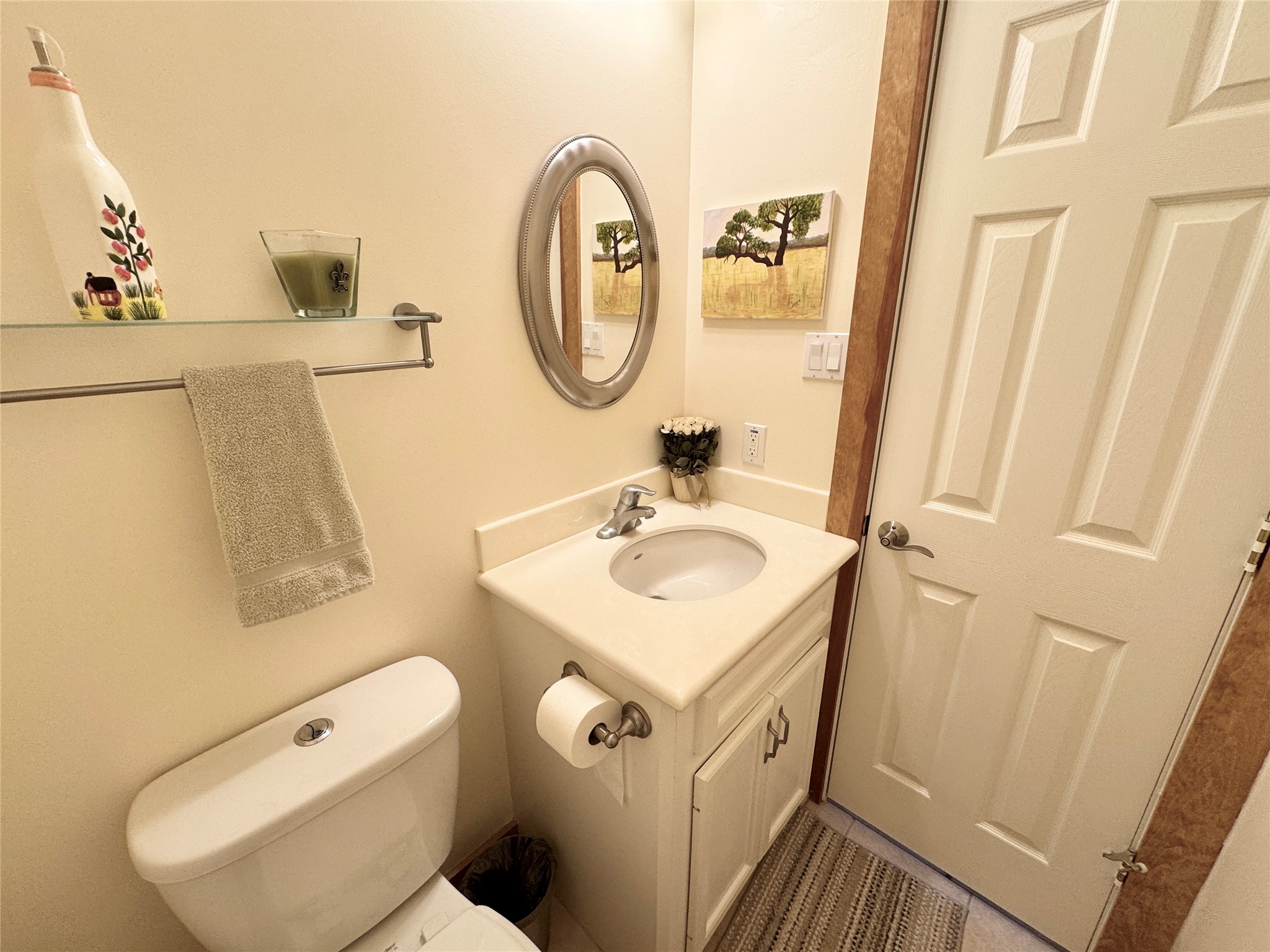 55 Lake Road Huntsville, TX 77320 - Photo 24 of 50 This half-bath features a compact vanity with an oval mirror, cultured marble vanity top and a shelf for toiletries. The neutral tones and simple decor create a cozy and functional space.