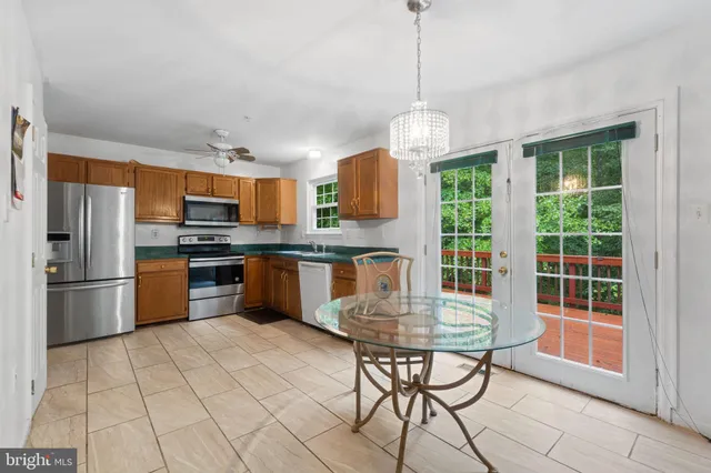 a kitchen with stainless steel appliances granite countertop a stove a refrigerator a sink dishwasher a dining table and chairs with wooden floor