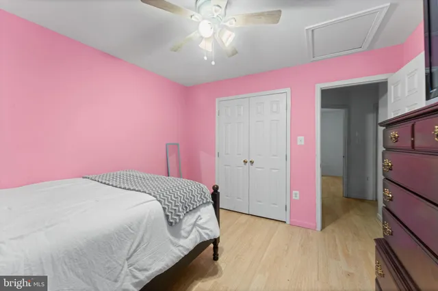 a spacious bedroom with pink walls and chandelier