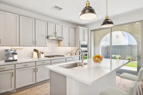 a kitchen with a sink dishwasher a stove and white cabinets with wooden floor