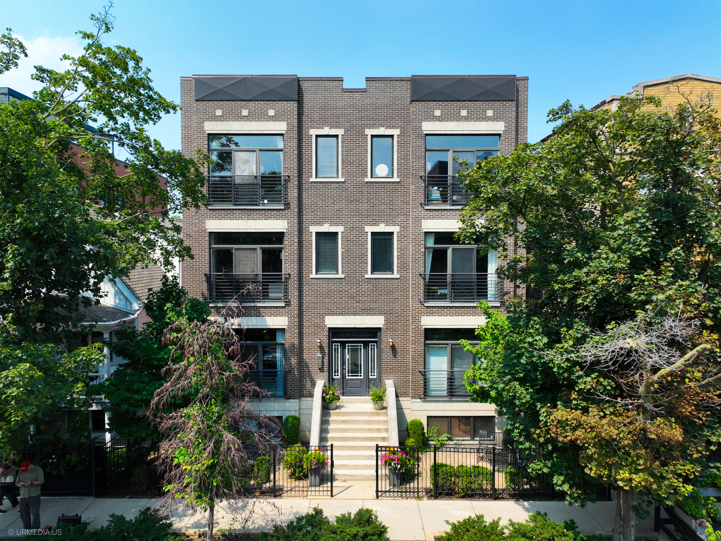 2242 West Roscoe Street, Unit 2 Chicago, IL 60618 - Photo 1 of 1 a front view of a residential apartment building with a yard and potted plants