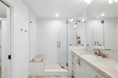 a bathroom with a granite countertop sink two mirror and shower
