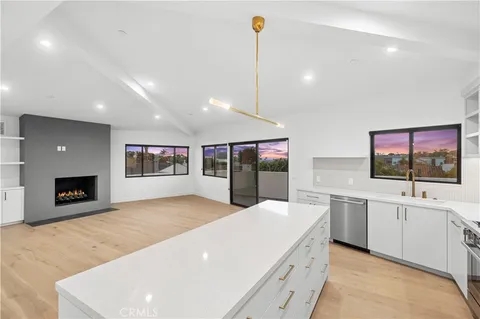 a large kitchen with stainless steel appliances a large counter top a stove a sink and a refrigerator