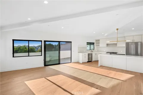 a large white kitchen with stainless steel appliances kitchen island a large counter top and a floors