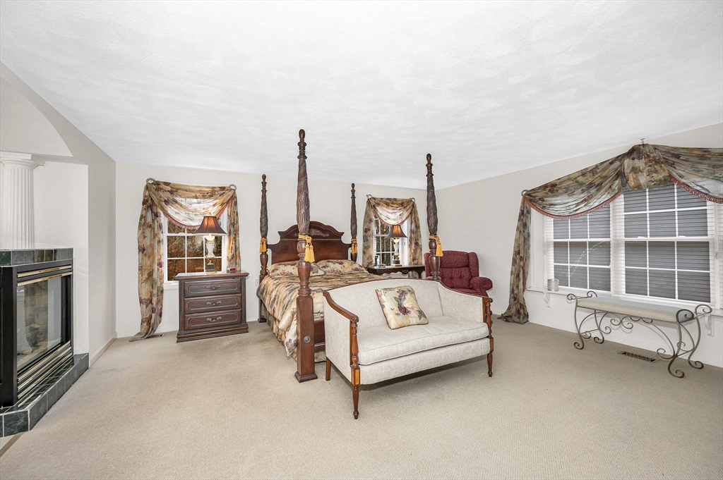 454 Dunstable Road Tyngsborough, MA 01879 - Photo 18 of 41 a spacious bedroom with a bed a couch and large window with outer view